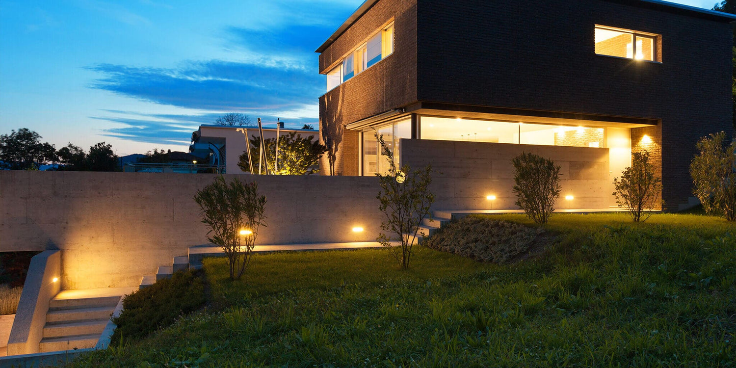 Led deck lights illuminating a home’s exterior at night, casting a gentle wash that defines paths and planting.